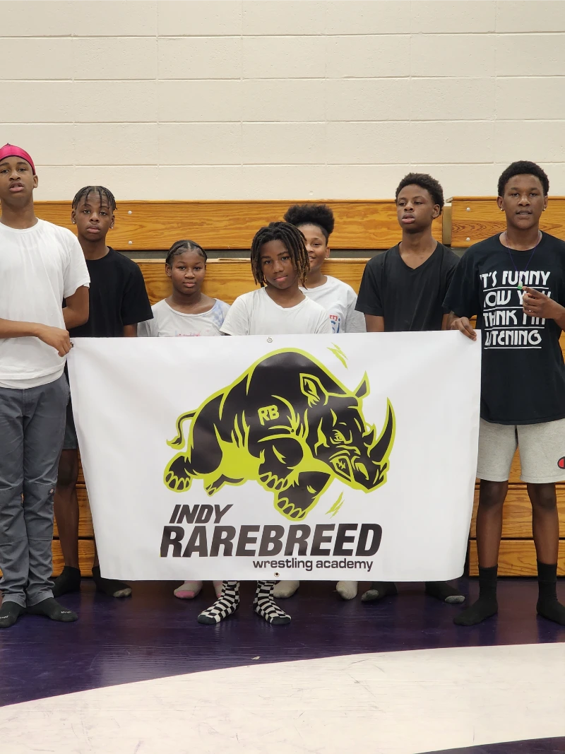 a group of wrestlers holding Indy Rarebreed Wrestling Academy flag