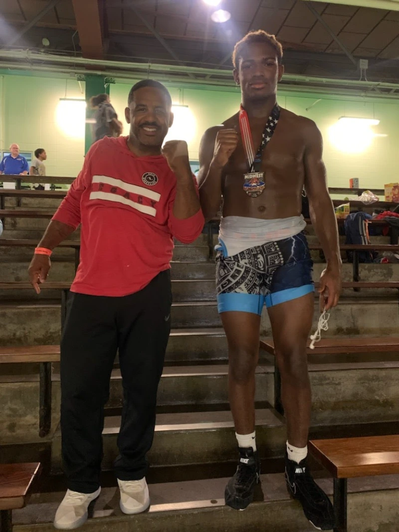 Coach standing beside his wrestler who won a medal