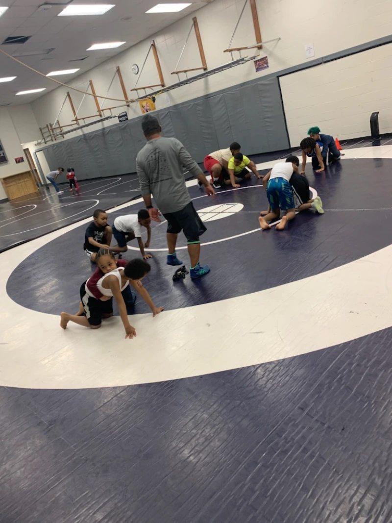  Coach teaching wrestling moves to his students by pairing them 