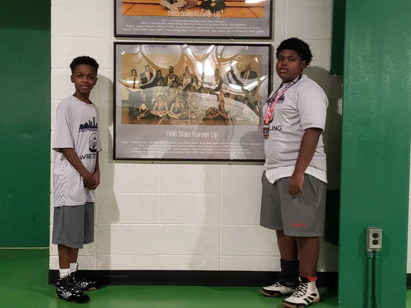 Two Young wrestling students showcasing the achievement of their academy team 