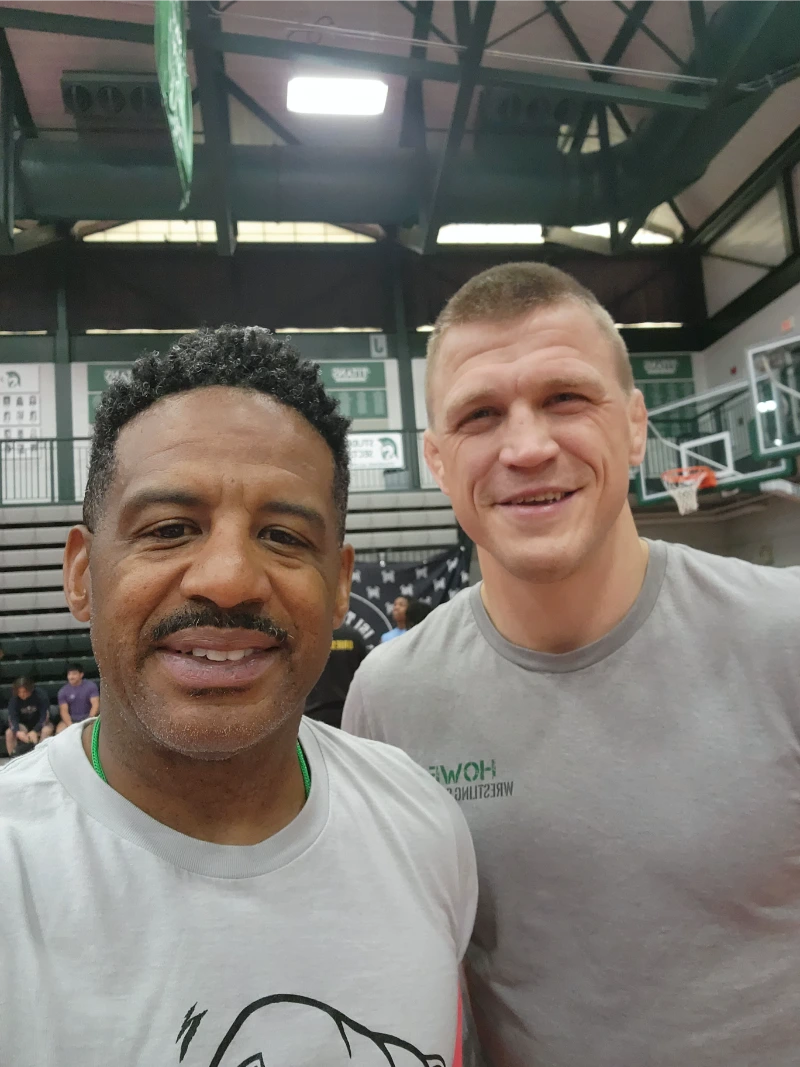 two men standing together in a wrestling gym